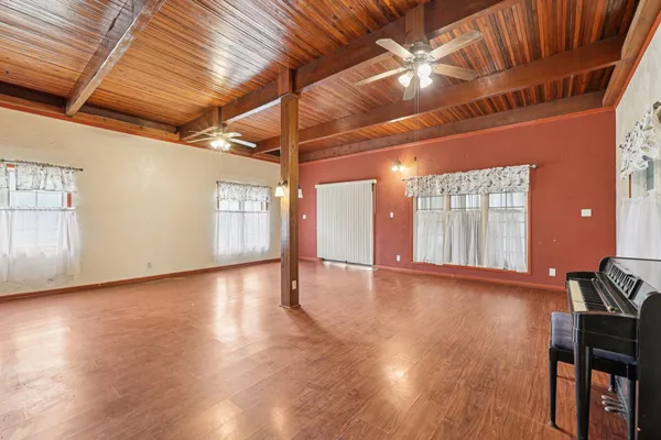 a view of an empty room with wooden floor and fan