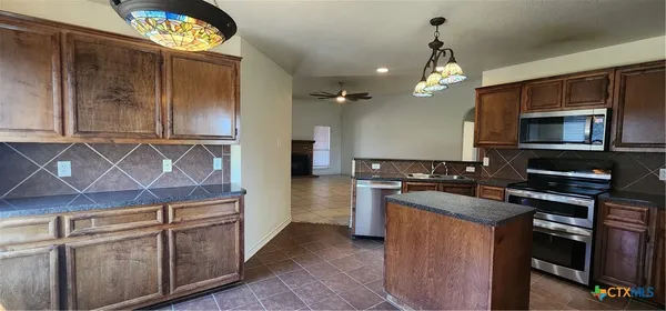a kitchen with kitchen island granite countertop a sink cabinets and stainless steel appliances