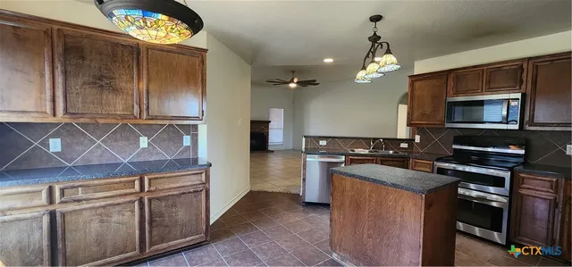 a kitchen with kitchen island granite countertop a sink cabinets and stainless steel appliances
