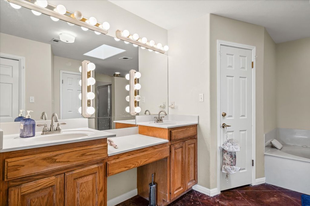 101 Valley Vista Road Wimberley, TX 78676 - Photo 15 of 23 The primary bath features a dual sink vanity, a large jetted tub, and a separate walk-in shower.