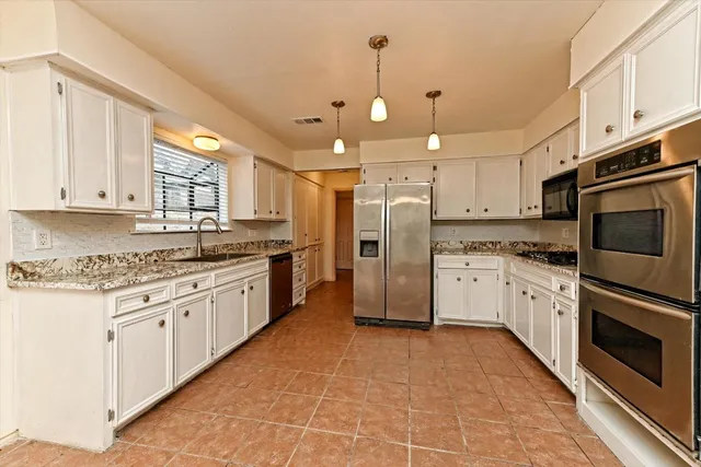 a large kitchen with stainless steel appliances granite countertop a stove a sink and a refrigerator