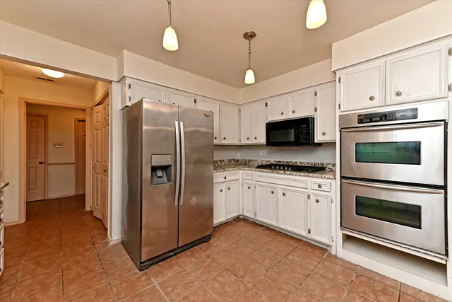 a kitchen with stainless steel appliances granite countertop a refrigerator and a stove top oven