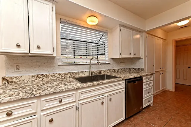 a kitchen with granite countertop a sink a stove and cabinets