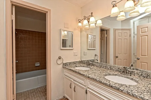 a bathroom with a granite countertop sink a mirror and a bathtub
