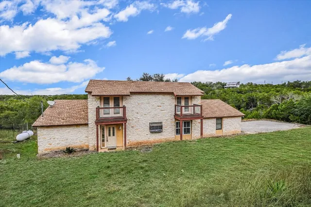 a view of a house with a big yard and large tree