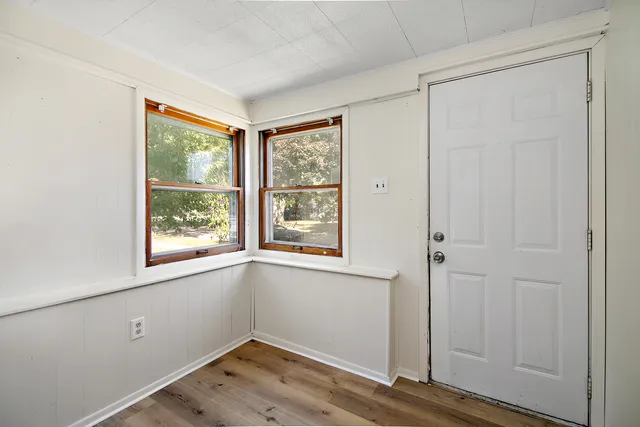 a view of an empty room with window and wooden floor