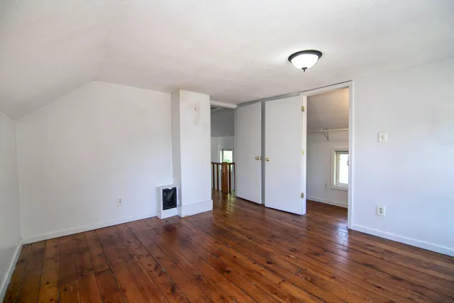 an empty room with a hardwood and windows