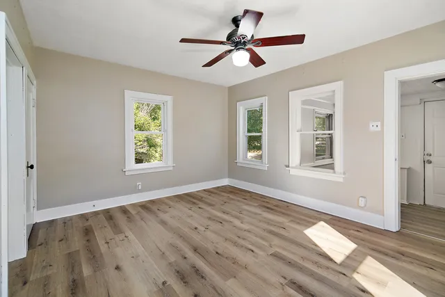 a view of empty room with wooden floor and fan