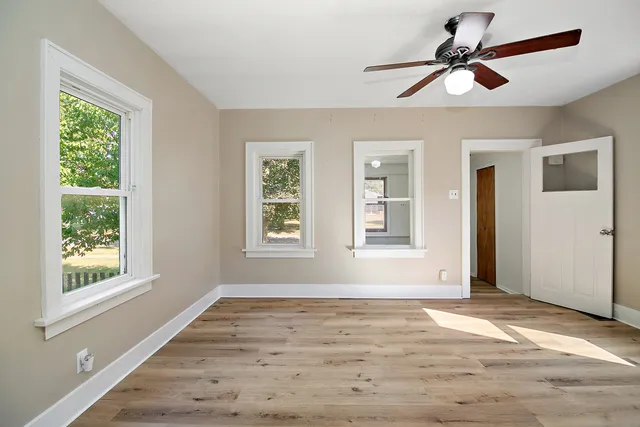 a view of an empty room with wooden floor and a window