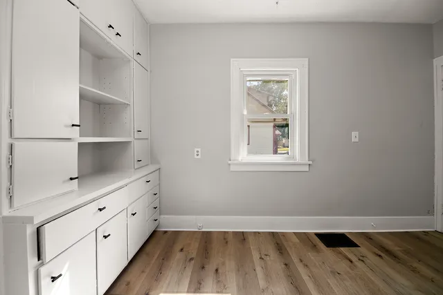a kitchen with white cabinets and wooden floor