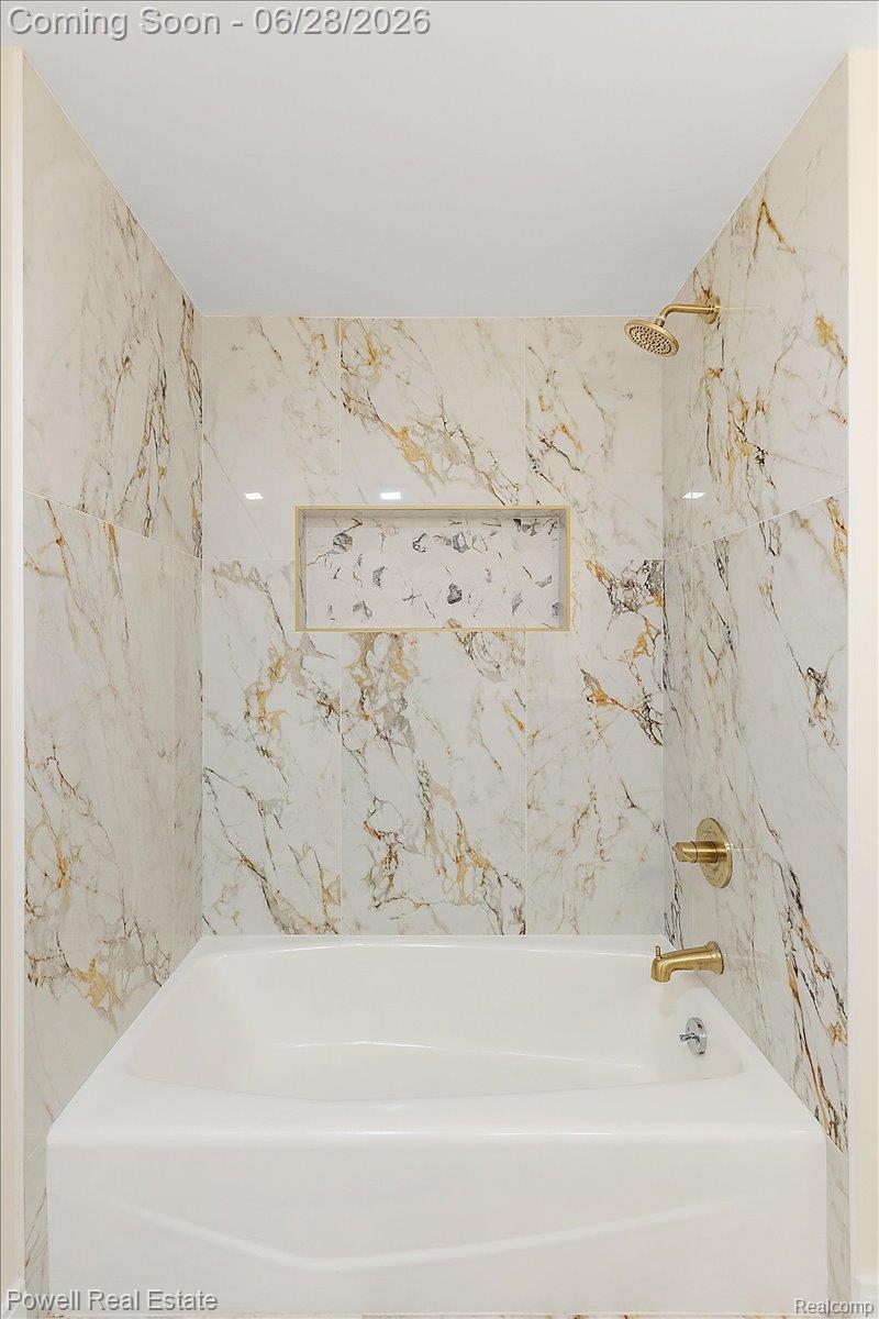 1447 Ravineview Court, Unit C12 Bloomfield Hills, MI 48304 - Photo 44 of 49 Bathtub and shower combination with floor-to-ceiling marbled tile surround