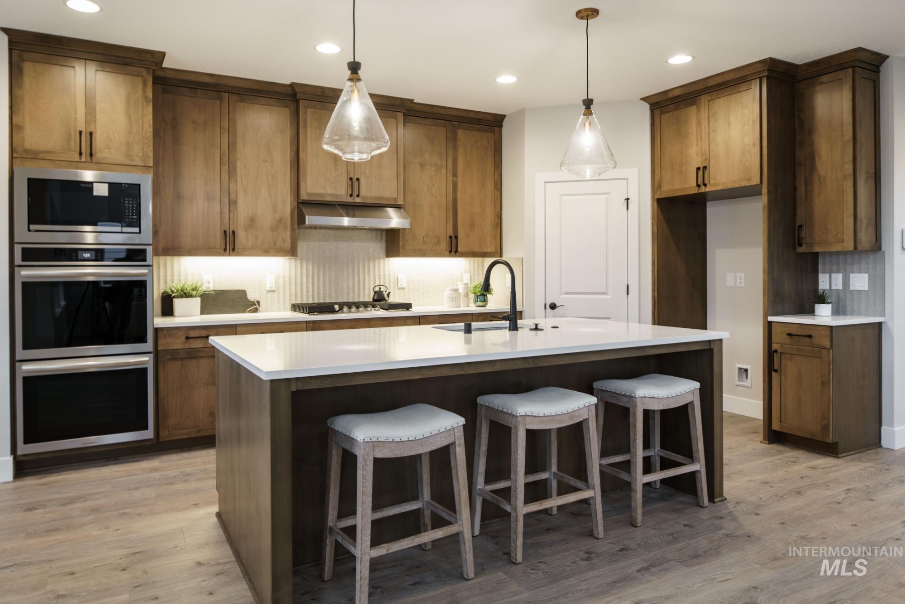 1009 West Malbar Street Meridian, ID 83646 - Photo 5 of 10 Kitchen with backsplash, appliances with stainless steel finishes, recessed lighting, light wood-type flooring, and an island with sink
