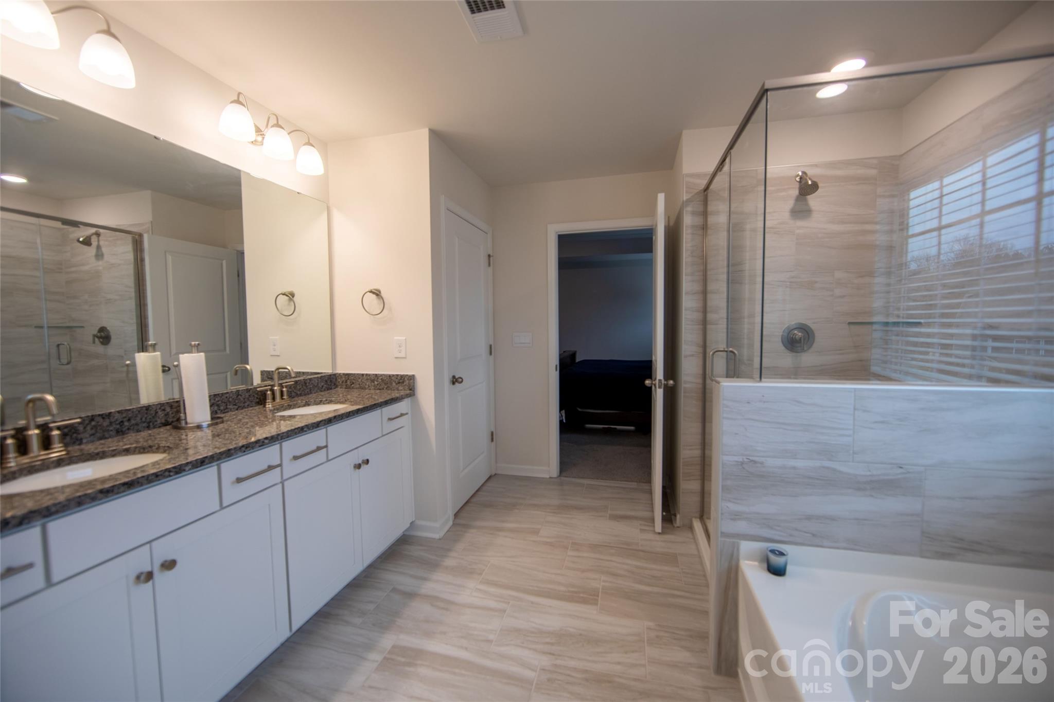 151 Aviendha Lane Troutman, NC 28166 - Photo 24 of 43 a spacious bathroom with a granite countertop sink mirror and shower