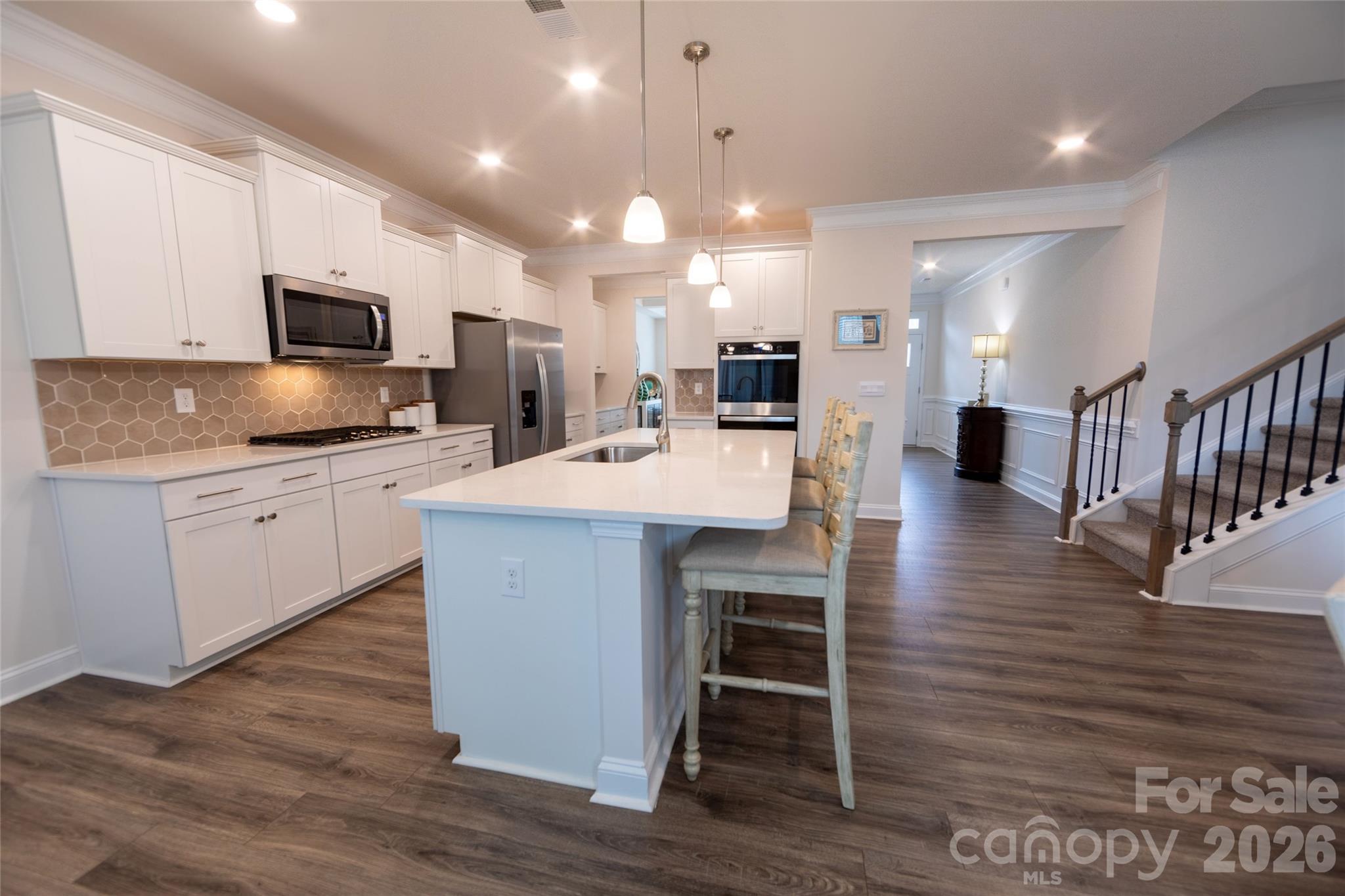 151 Aviendha Lane Troutman, NC 28166 - Photo 9 of 43 a kitchen with stainless steel appliances kitchen island granite countertop a stove top oven a sink a dining table and chairs