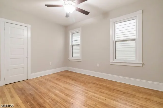 a view of empty room with wooden floor and fan