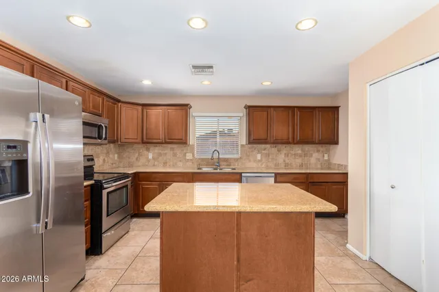 a kitchen with stainless steel appliances granite countertop a sink a stove a microwave a center island and cabinets