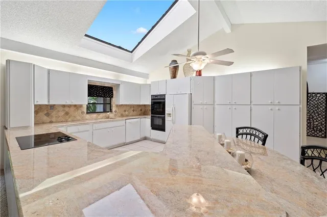 a kitchen with granite countertop a stove a sink and a refrigerator with wooden floor