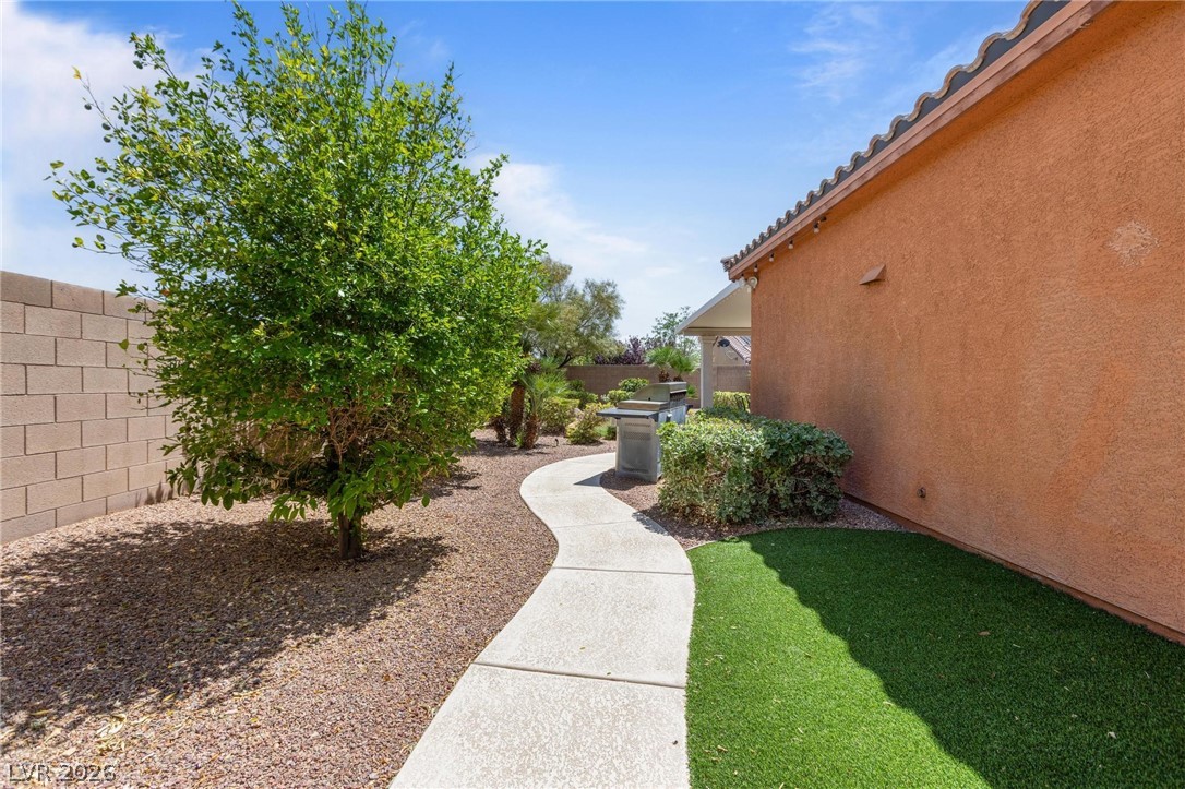 8431 Durango Ranch Court Las Vegas, NV 89113 - Photo 34 of 49 This serene backyard features a paved pathway and lush greenery, perfect for outdoor enjoyment.
