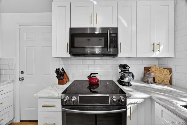 a kitchen with stainless steel appliances granite countertop white cabinets stove top oven and sink