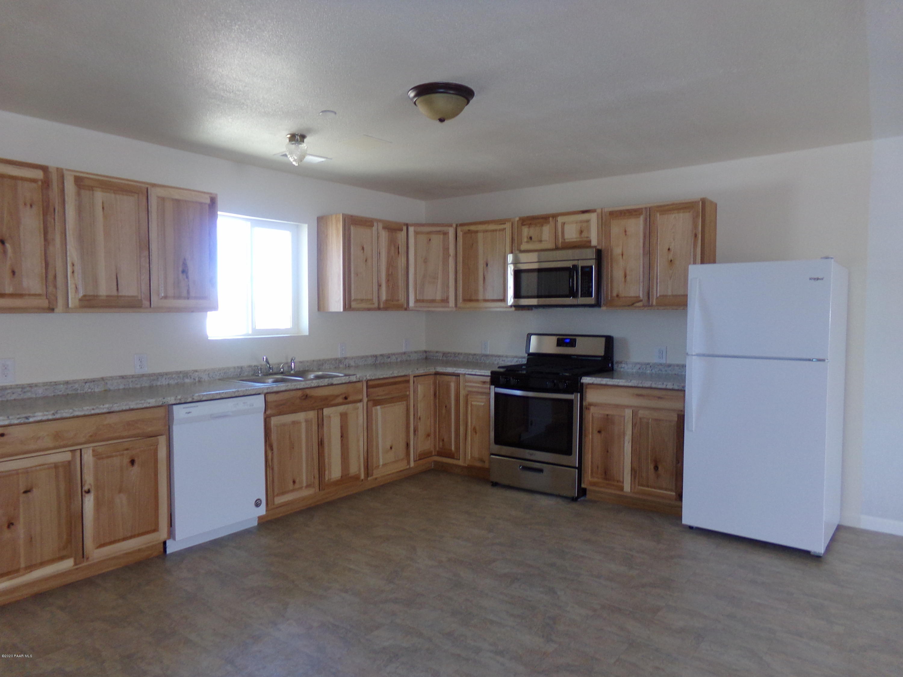 3100 Bob Court, Unit 2 Prescott Valley, AZ 86314 - Photo 3 of 10 a kitchen with granite countertop a refrigerator and a stove top oven