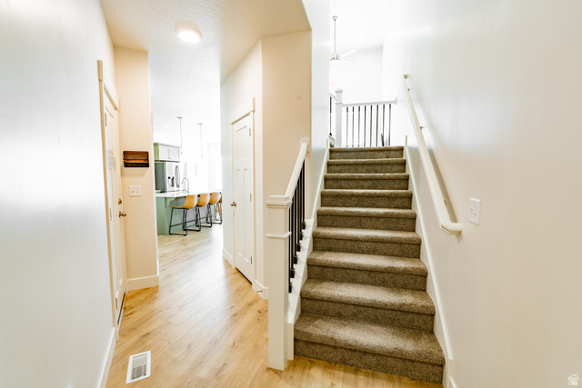 4881 Heartwood Road Mapleton, UT 84664 - Photo 3 of 25 Carpeted staircase with white balusters and dark spindles leading to a landing with a ceiling fan
