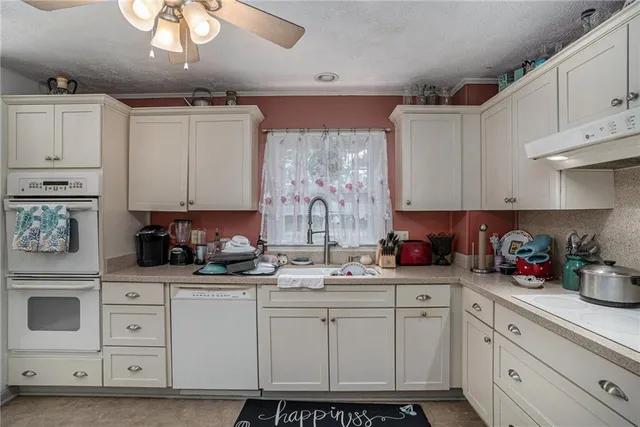 a kitchen with white cabinets and window