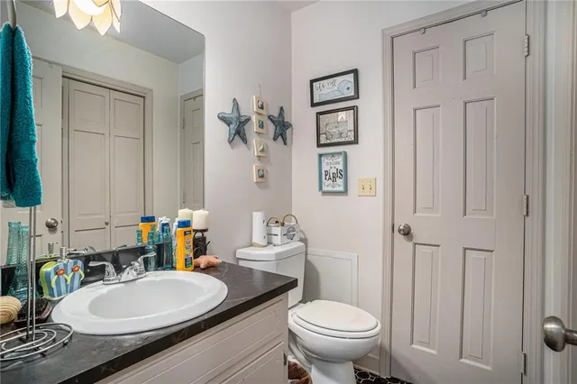 a bathroom with a granite countertop toilet a sink and a mirror