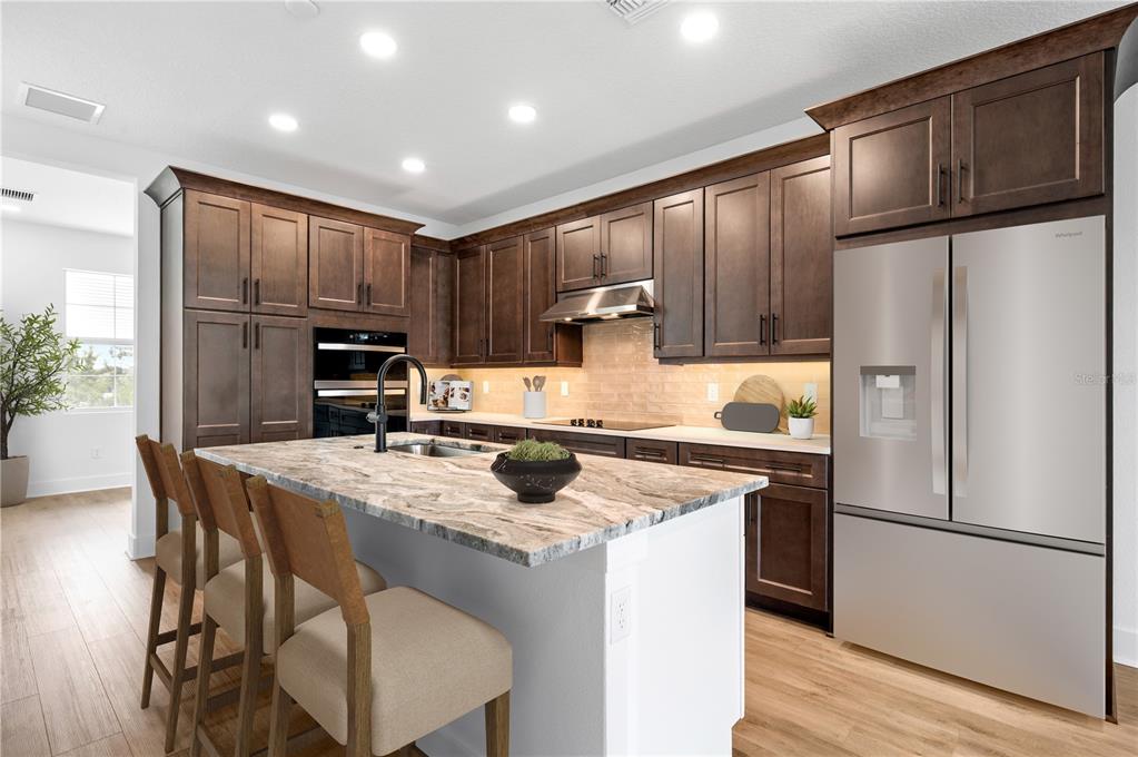 9975 Key Haven Road Seminole, FL 33777 - Photo 11 of 56 a kitchen with kitchen island granite countertop wooden cabinets a refrigerator a stove a sink and a refrigerator with wooden floor