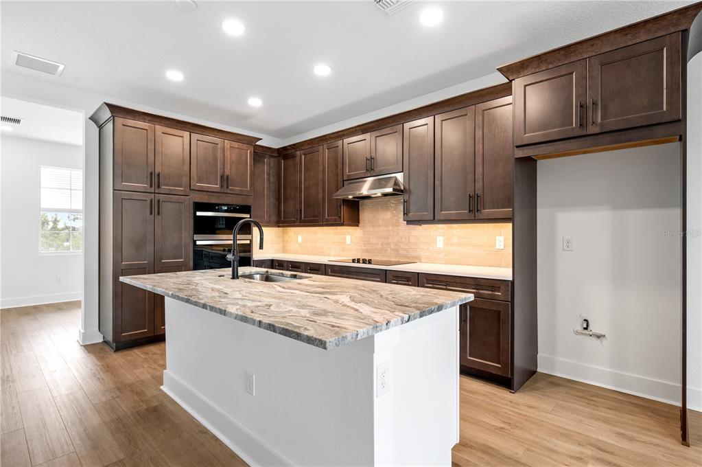 9975 Key Haven Road Seminole, FL 33777 - Photo 13 of 56 a kitchen with kitchen island granite countertop wooden cabinets a sink and a stove