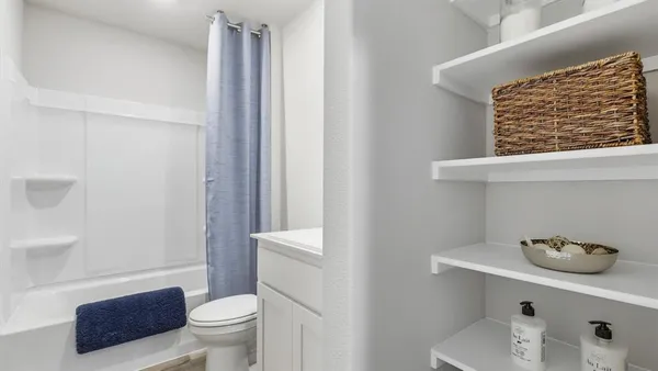 a bedroom with a bed and a lamp on dresser