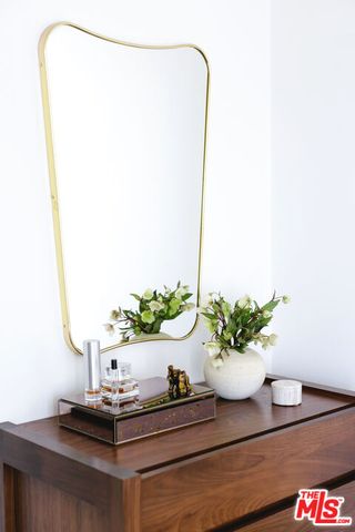 a bedroom with a bed and a potted plant on the dresser