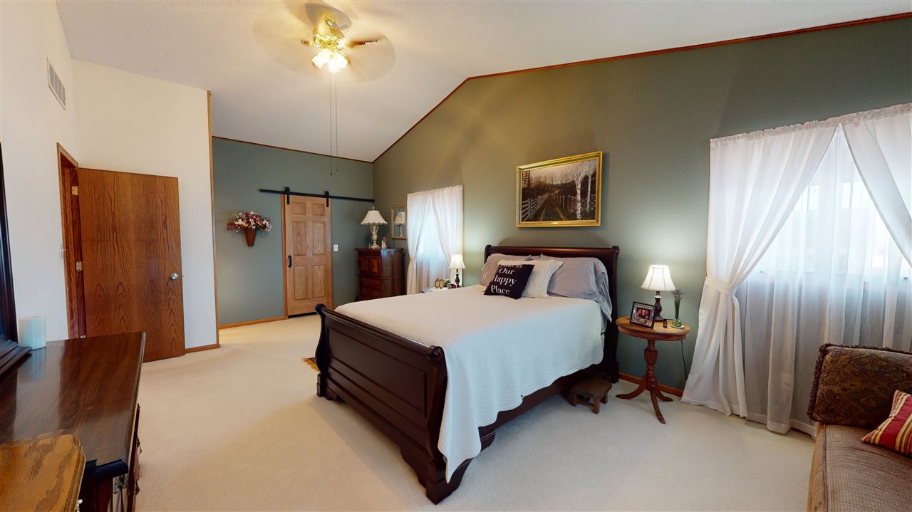 3028 South Golf Road Stockton, IL 61085 - Photo 20 of 26 a spacious bedroom with a bed and a chandelier