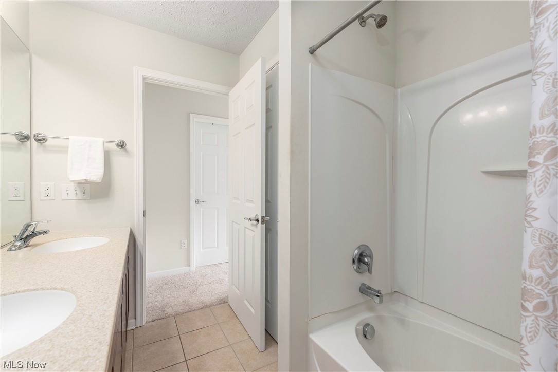 3967 Gardiner Run Akron, OH 44321 - Photo 25 of 35 Bathroom with a textured ceiling, light tile flooring, dual vanity, mirror, and shower / bath combination with curtain