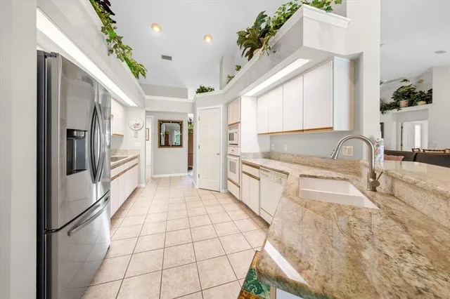 a large white kitchen with granite countertop a sink window and refrigerator