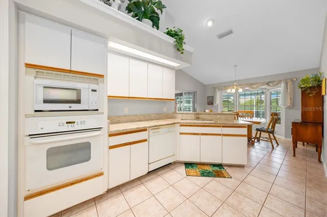 a kitchen with granite countertop white cabinets and white appliances