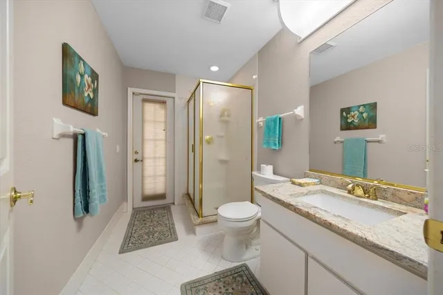 a spacious bathroom with a granite countertop sink a toilet a mirror and shower