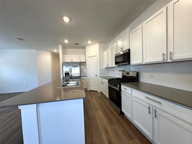 a view of a big room with wooden floor a ceiling fan and windows