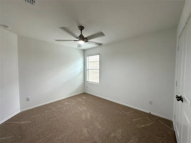 an empty room with a chandelier fan and windows