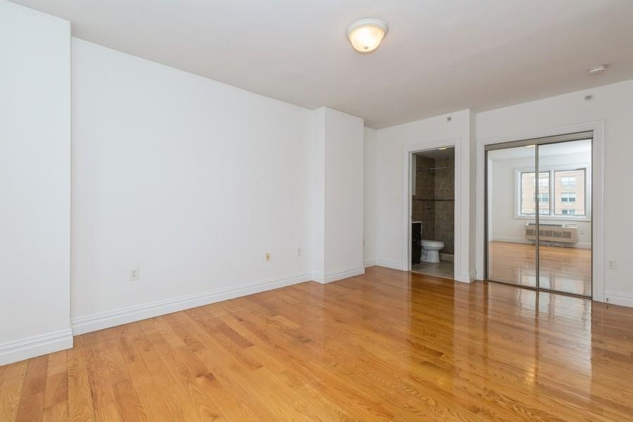 125 43rd Street, Unit 504 Union City, NJ 07087 - Photo 7 of 16 a view of an empty room with wooden floor and a window