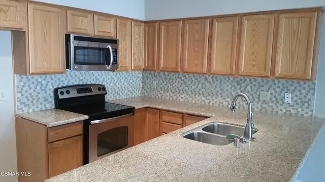 a kitchen with granite countertop a sink dishwasher stove and cabinets with wooden floor