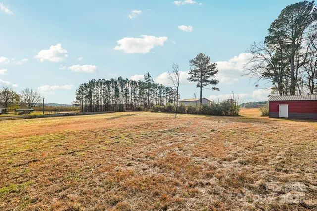 a backyard of a house with large trees and wooden fence
