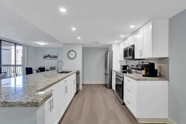 a large kitchen with stainless steel appliances granite countertop a lot of counter space and wooden floor