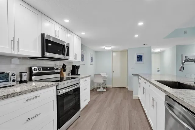 a large kitchen with stainless steel appliances granite countertop a stove a sink and a microwave