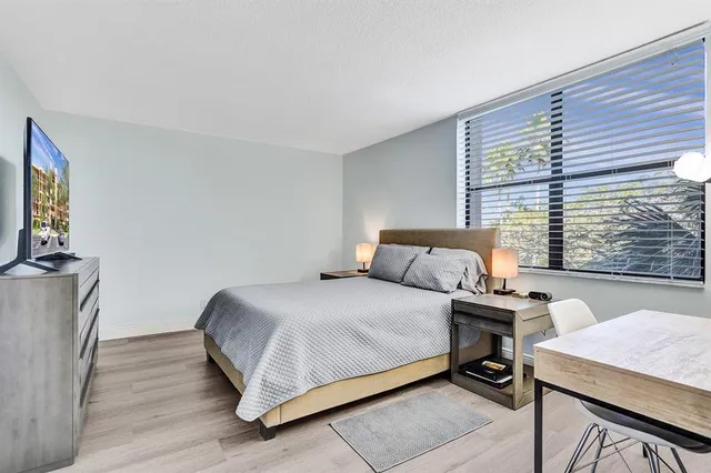 a bedroom with a bed a table and a flat screen tv