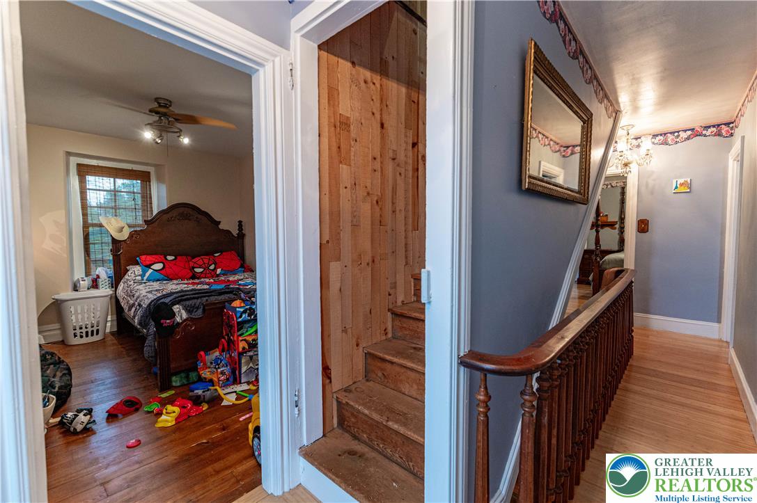 2485 Hieter Road Quakertown, PA 18951 - Photo 48 of 97 Hardwood floors stretch through a bedroom and continue into the hallway, complemented by a rustic wooden staircase.