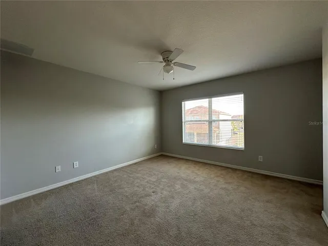 an empty room with closet and a ceiling fan