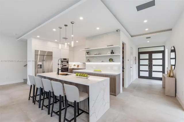a kitchen with kitchen island a dining table chairs stainless steel appliances and cabinets