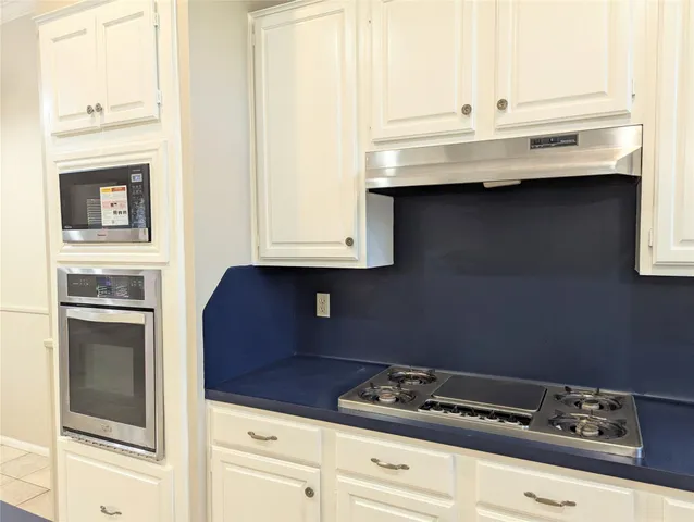 a kitchen with granite countertop white cabinets and white appliances