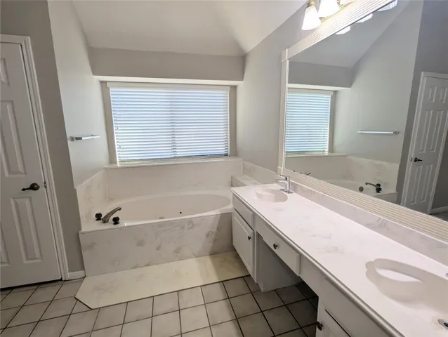 a bathroom with a tub sink and mirror