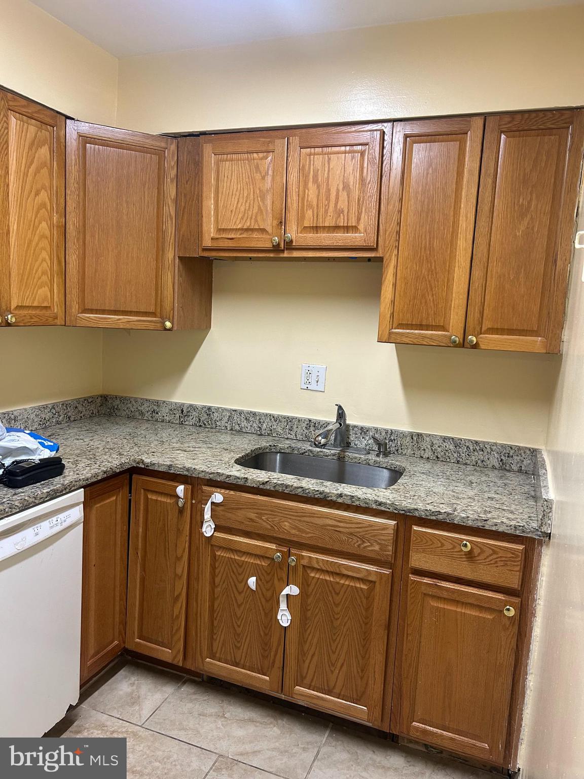 9250 Edwards Way, Unit 103A Hyattsville, MD 20783 - Photo 7 of 8 a kitchen with granite countertop a sink cabinets and stainless steel appliances